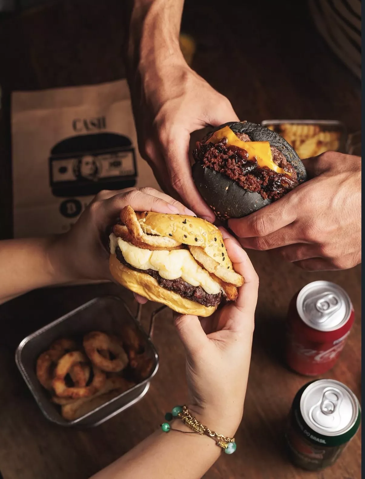 Duas pessoas dividindo burgers da Cash Burger sobre a mesa